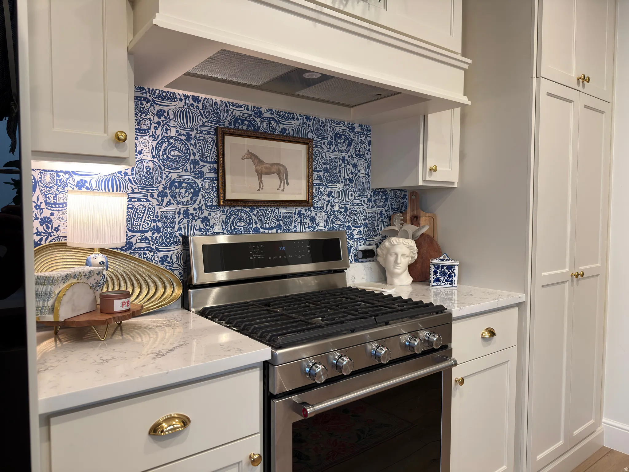 Kitchen featuring a stainless steel range with gas burners, a matching range hood, and a blue and white patterned backsplash