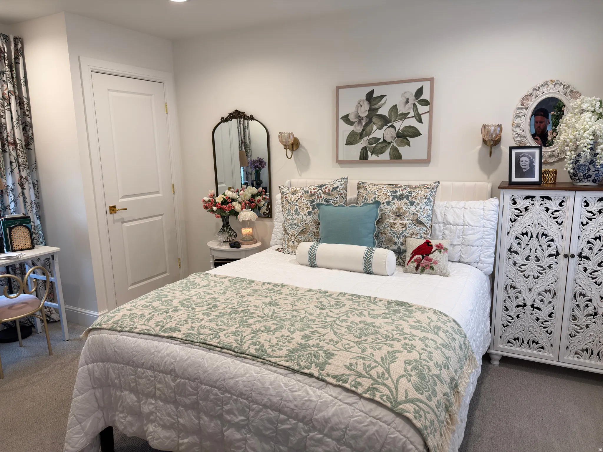 Recessed lighting illuminates a space featuring a paneled interior door with brass hardware, a decorative wall mirror, and dual wall sconces