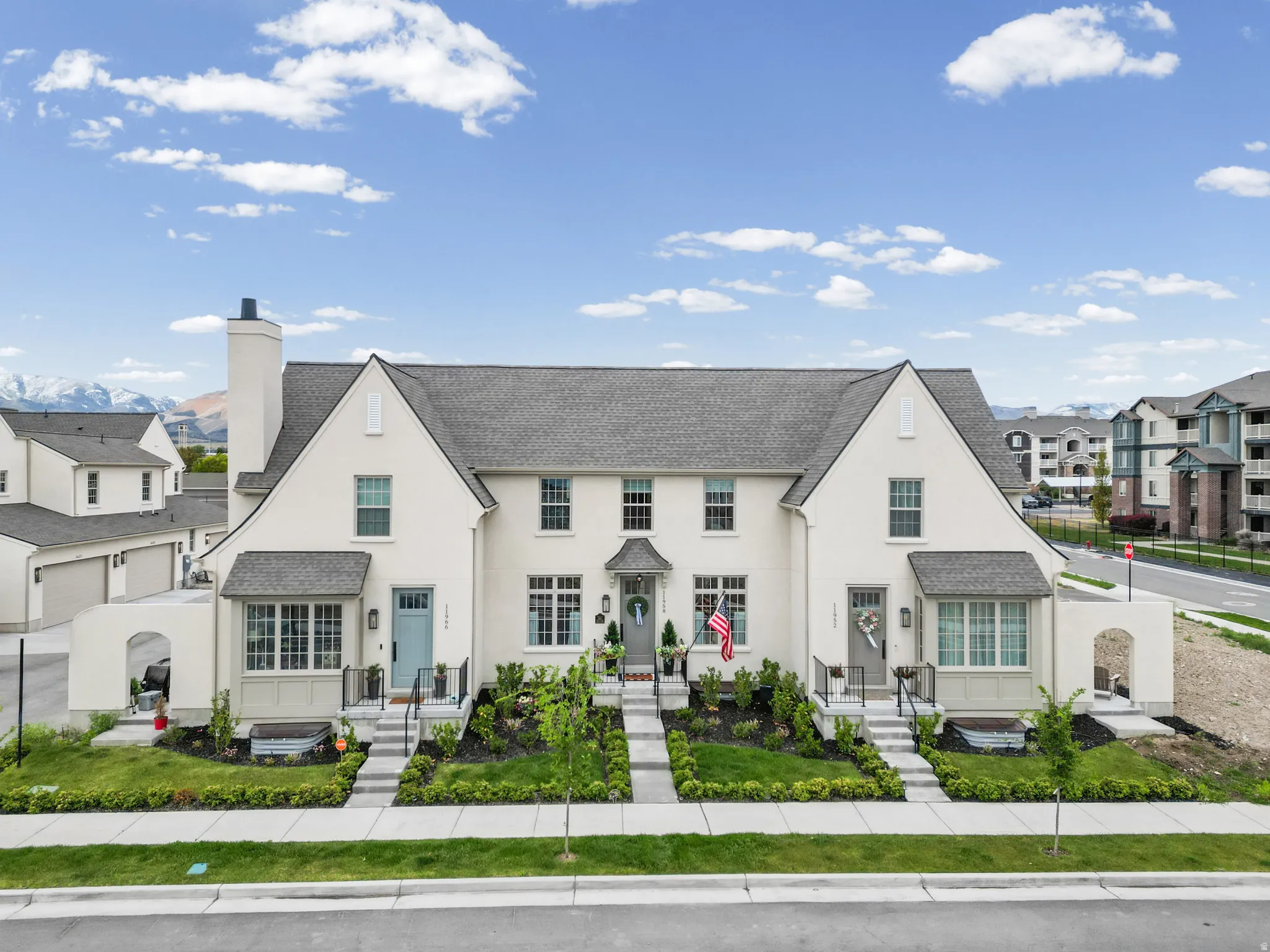 Contemporary townhome with a light stucco exterior and a dark gray shingle roof