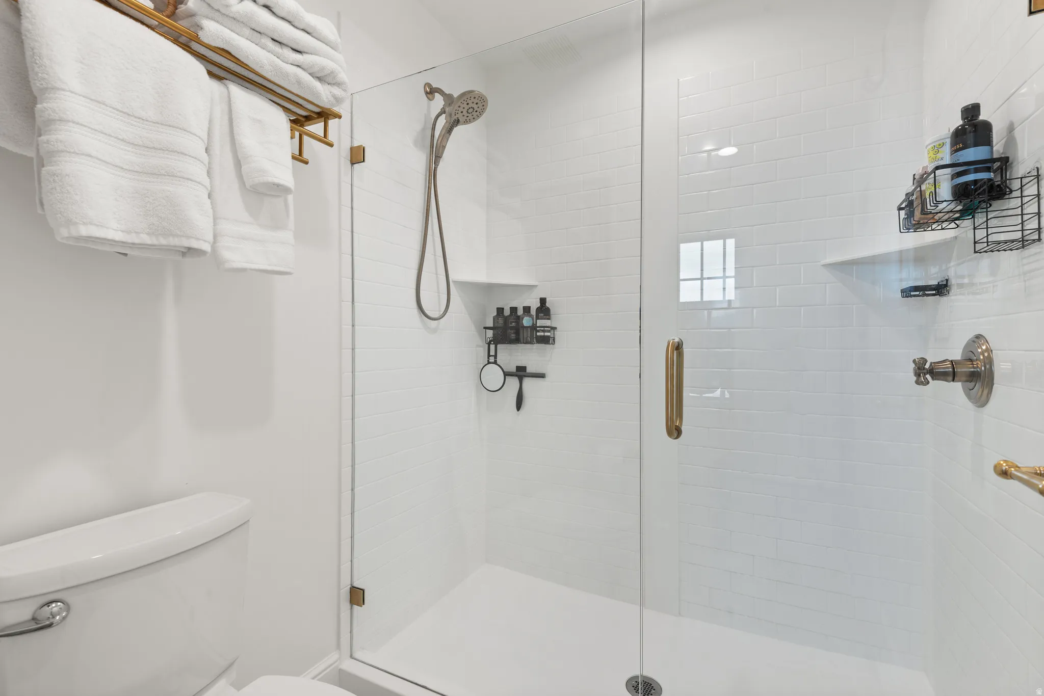 Walk-in shower with clear glass enclosure and brushed brass hardware