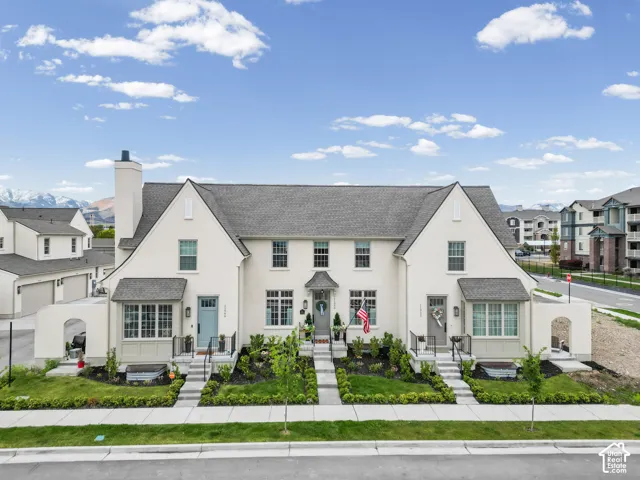 Contemporary townhome with a light stucco exterior and a dark gray shingle roof