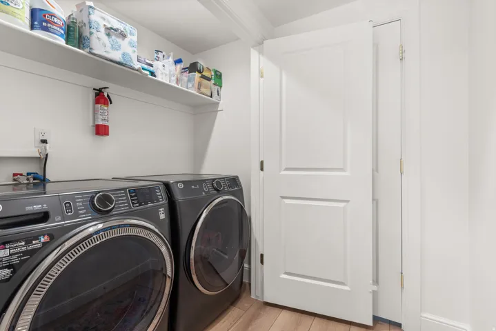 Laundry area featuring wood-finish flooring and bright white walls