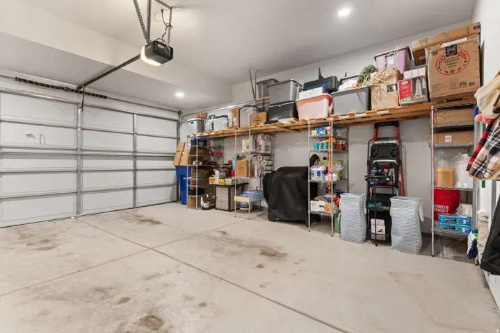 Spacious garage featuring a sectional overhead door, automatic opener, concrete flooring and EV charger.