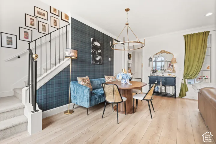 Inviting living area featuring light wood-finish flooring, a contemporary candelabra chandelier, a staircase with a black wrought iron railing with brass tops imported from Africa.