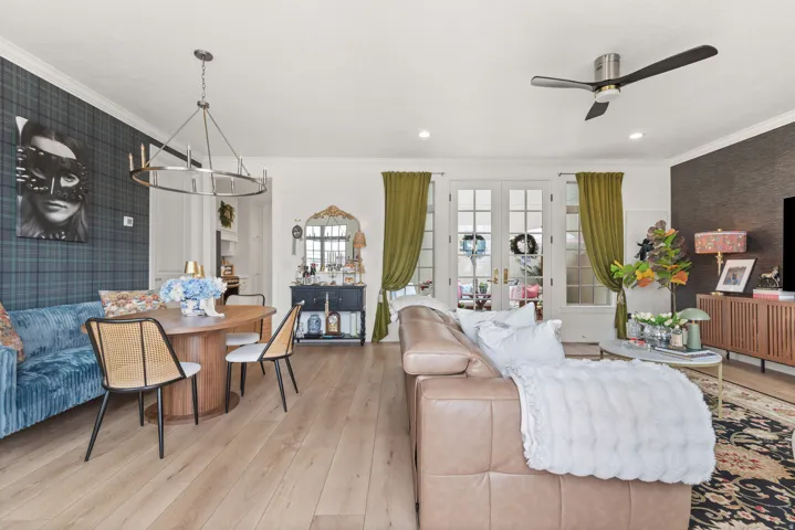Open-concept living space featuring wood-finish flooring, a contemporary chandelier, crown molding, and recessed lighting
