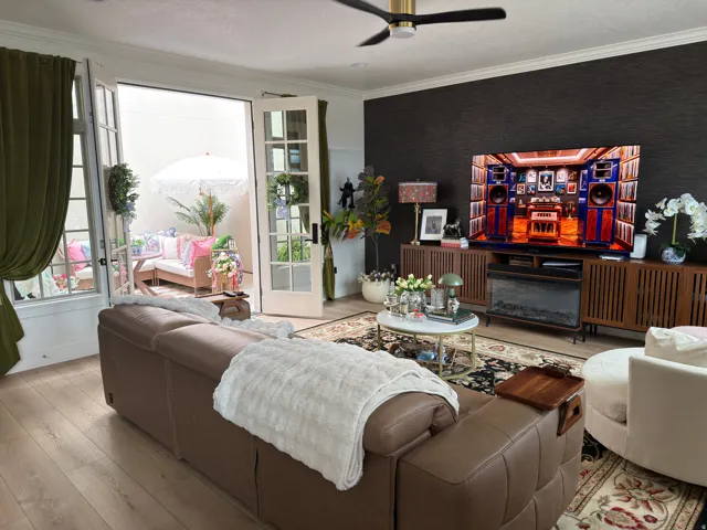 Living area featuring light wood-finish flooring, a dark accent wall, and a gold and black ceiling fan