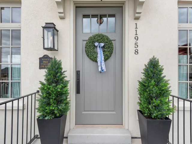 Entryway featuring a grey paneled door with window inserts, stucco exterior, and black wrought iron railings