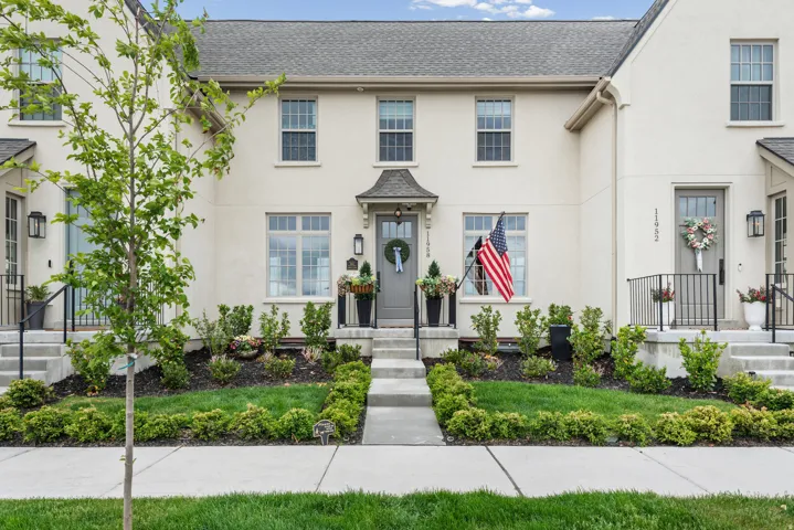 Stucco exterior with a gabled entry, concrete pathway, and decorative landscaping