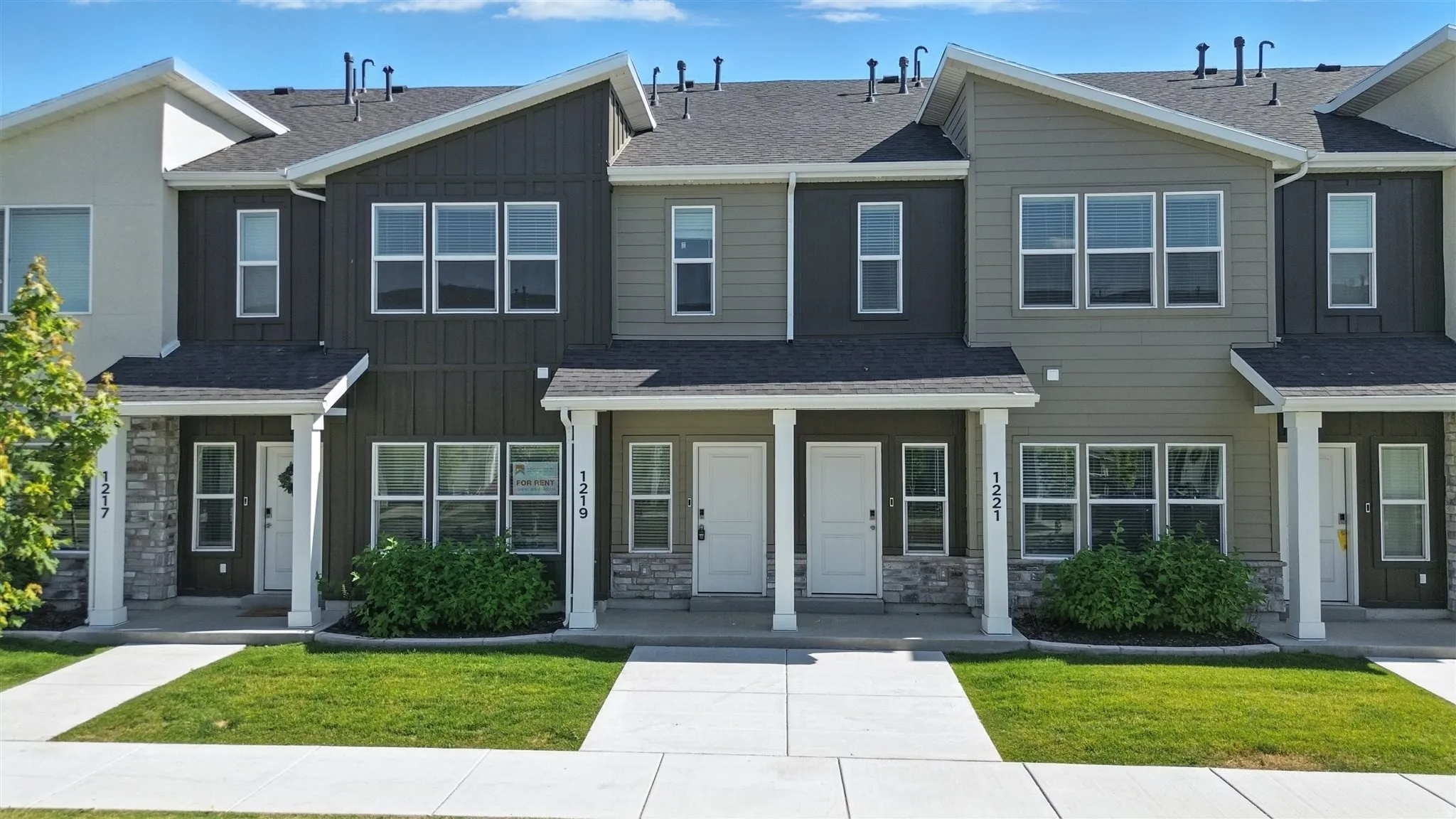 Modern townhome exteriors featuring varied siding materials and stone accents