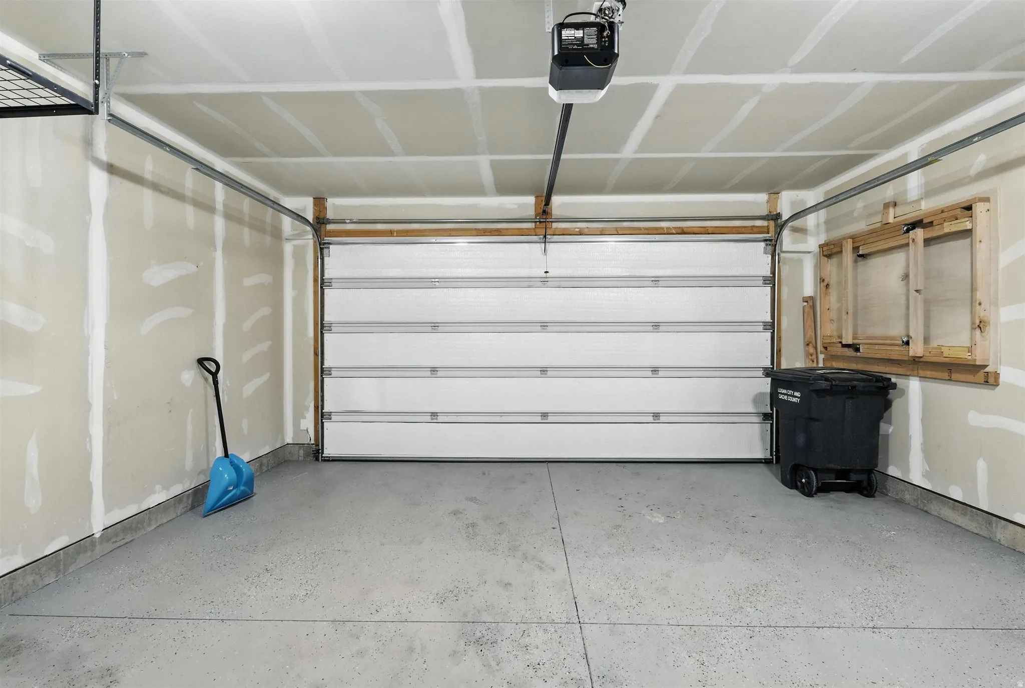 Attached garage featuring a white sectional door with automatic opener
