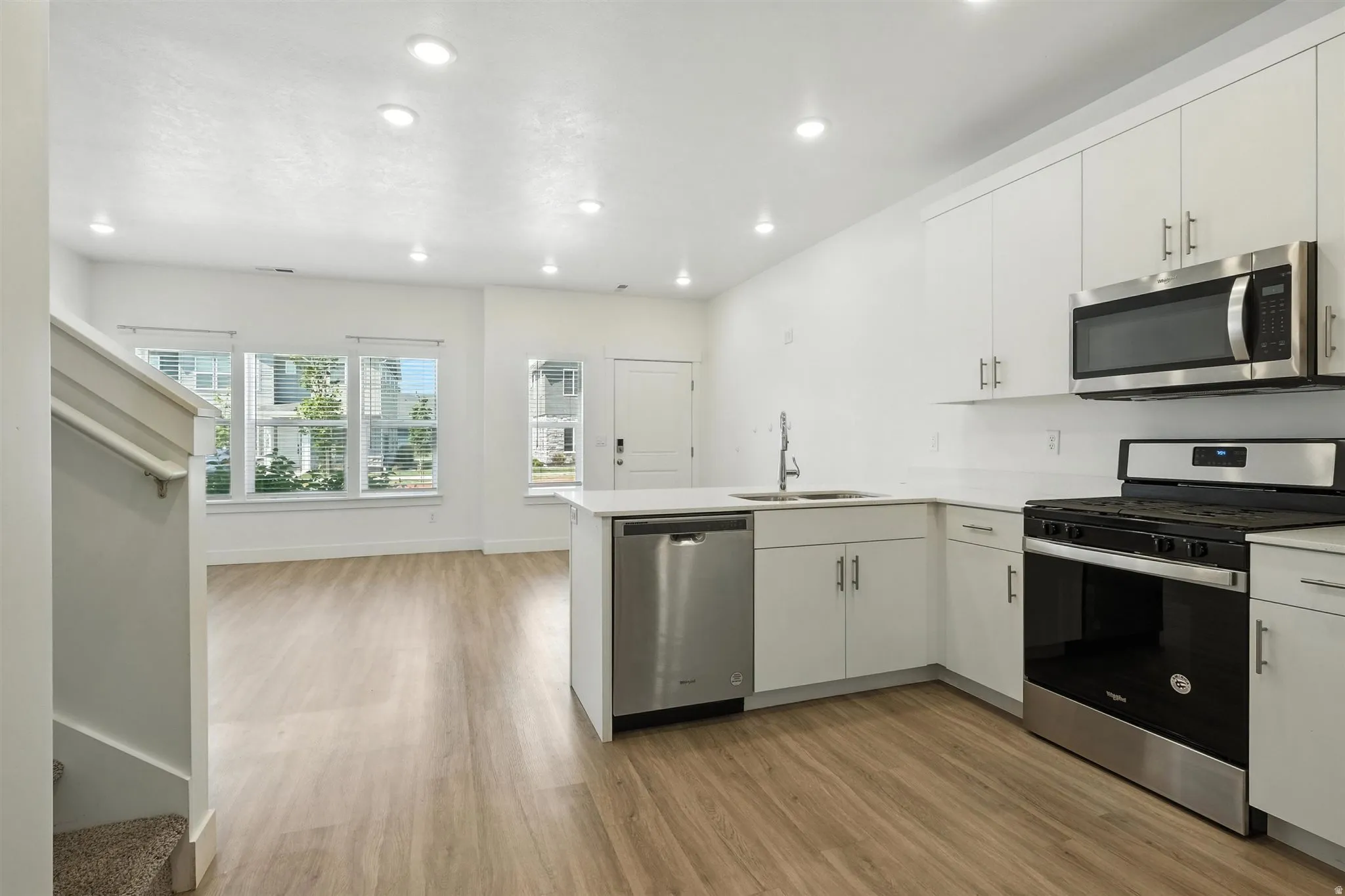 Modern kitchen featuring white cabinetry, stainless steel appliances, light countertops, and recessed lighting