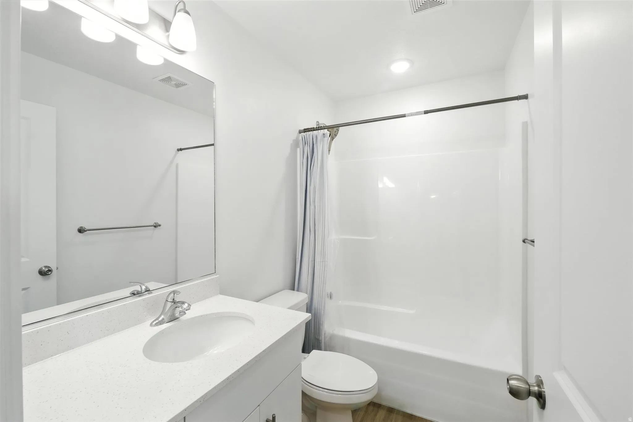 Bathroom featuring a white vanity with an integrated sink, polished chrome faucet, and expansive wall-mounted mirror