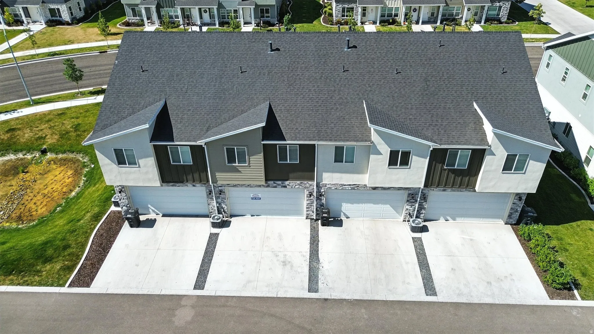 Modern townhome featuring a dark shingle roof and a multi-textured facade