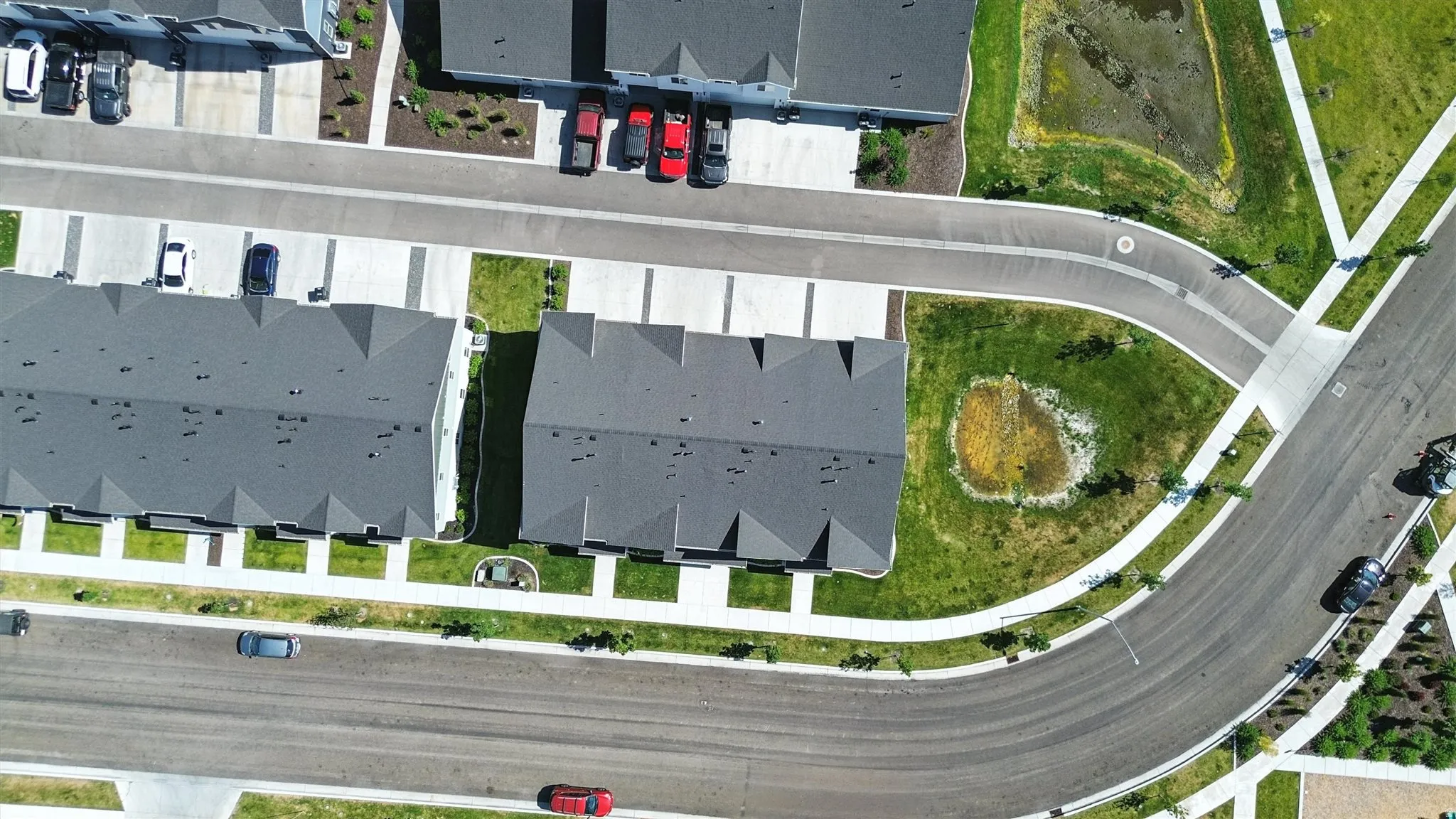 Aerial perspective showcasing a community with multiple residential buildings featuring dark gray shingle roofs