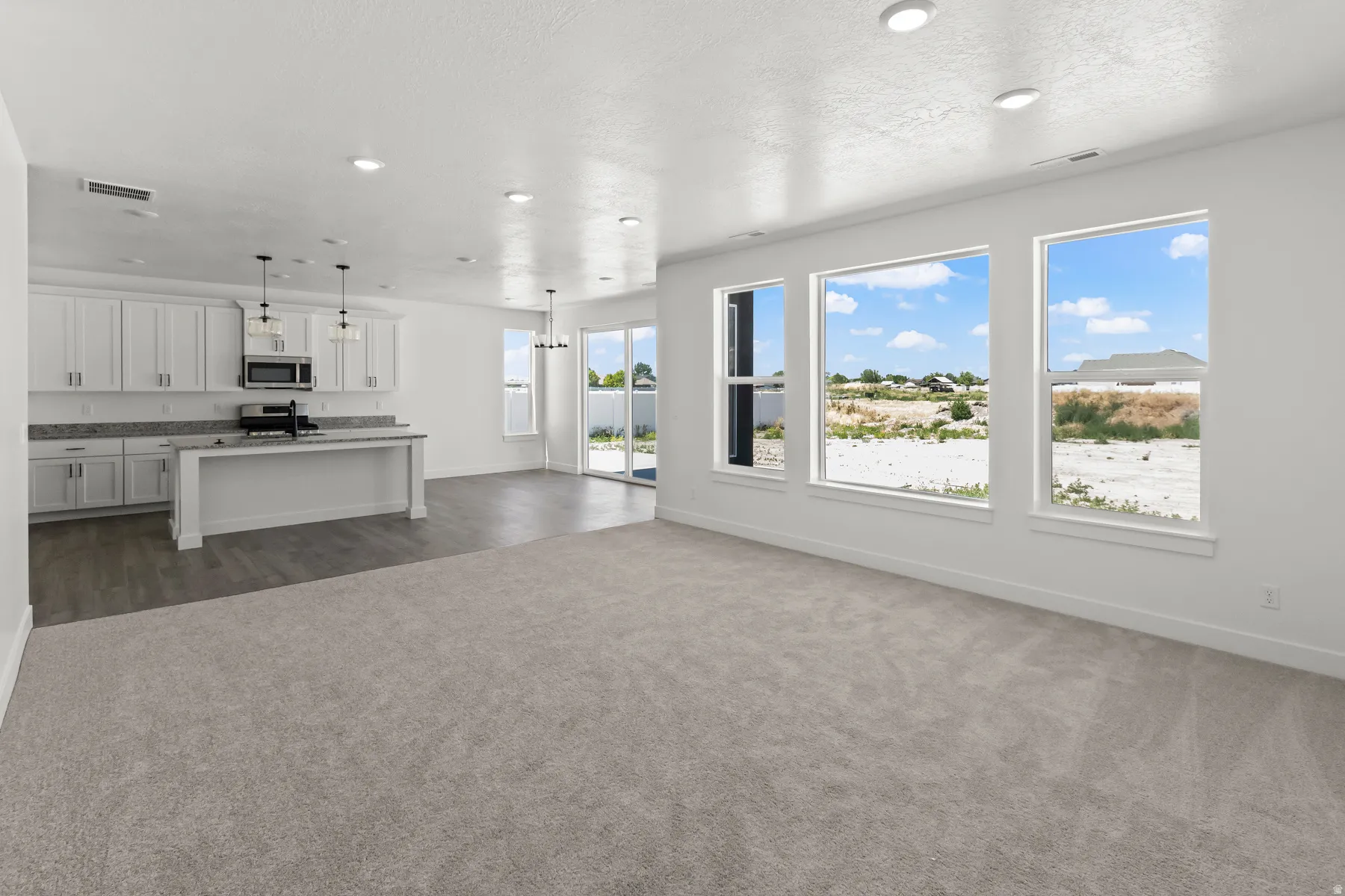 Open-concept living space, a kitchen with white cabinetry and recessed lighting