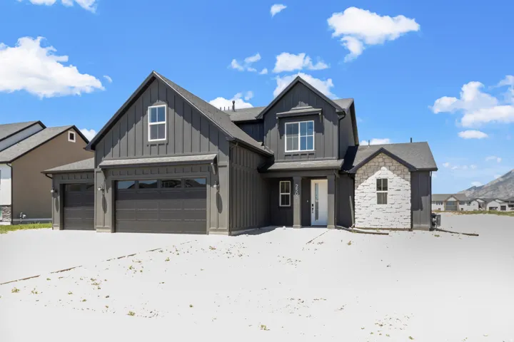 Modern farmhouse-style exterior featuring dark vertical siding and a light stone facade