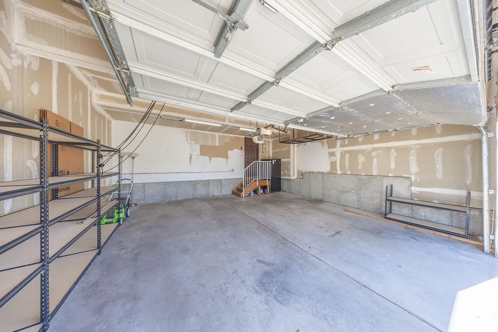 Spacious garage with concrete flooring and shelving.