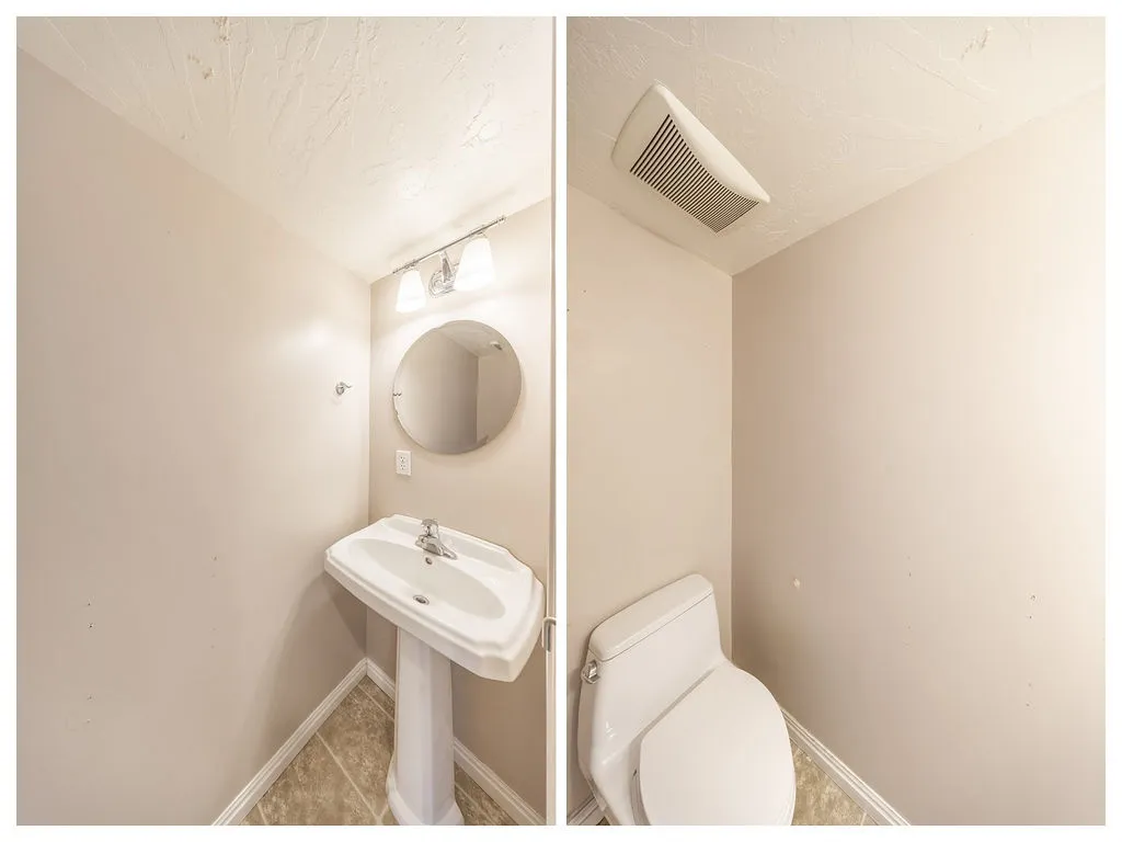 Powder room featuring a pedestal sink, round wall mirror, and a two-bulb vanity light fixture