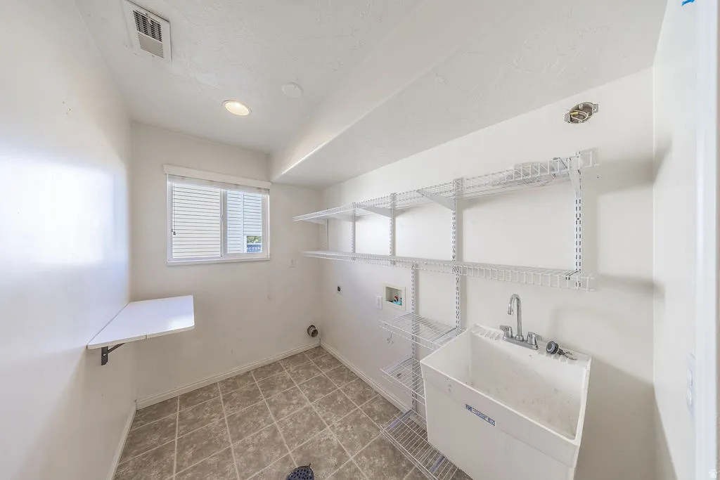 Laundry room featuring a utility sink, wall-mounted wire shelving, a built-in folding table, and a window.