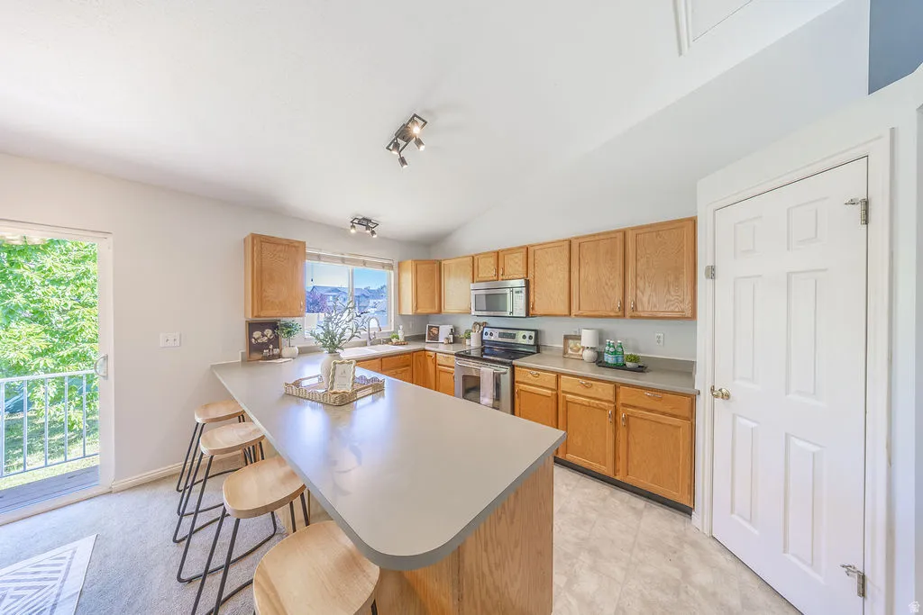 Kitchen featuring light wood cabinetry, stainless steel appliances, a large island with counter seating, track lighting, and PANTRY!