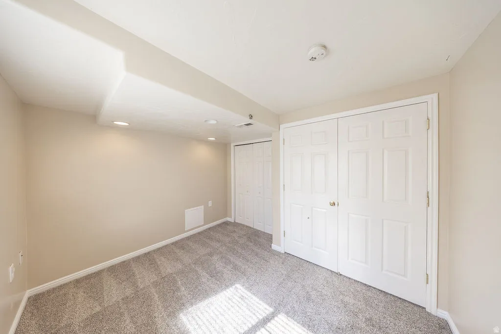 Bedroom #4 featuring neutral-toned walls, recessed lighting, neutral colored carpet, and closets.