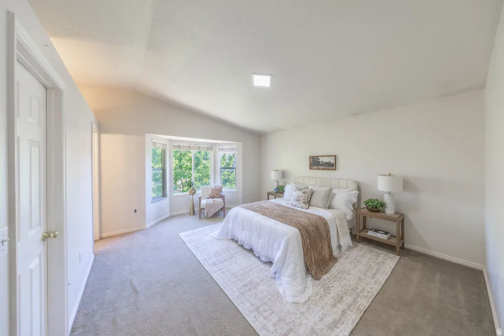 Vaulted ceiling room featuring a wide bay window, neutral carpet, WIC, and en suite bath.