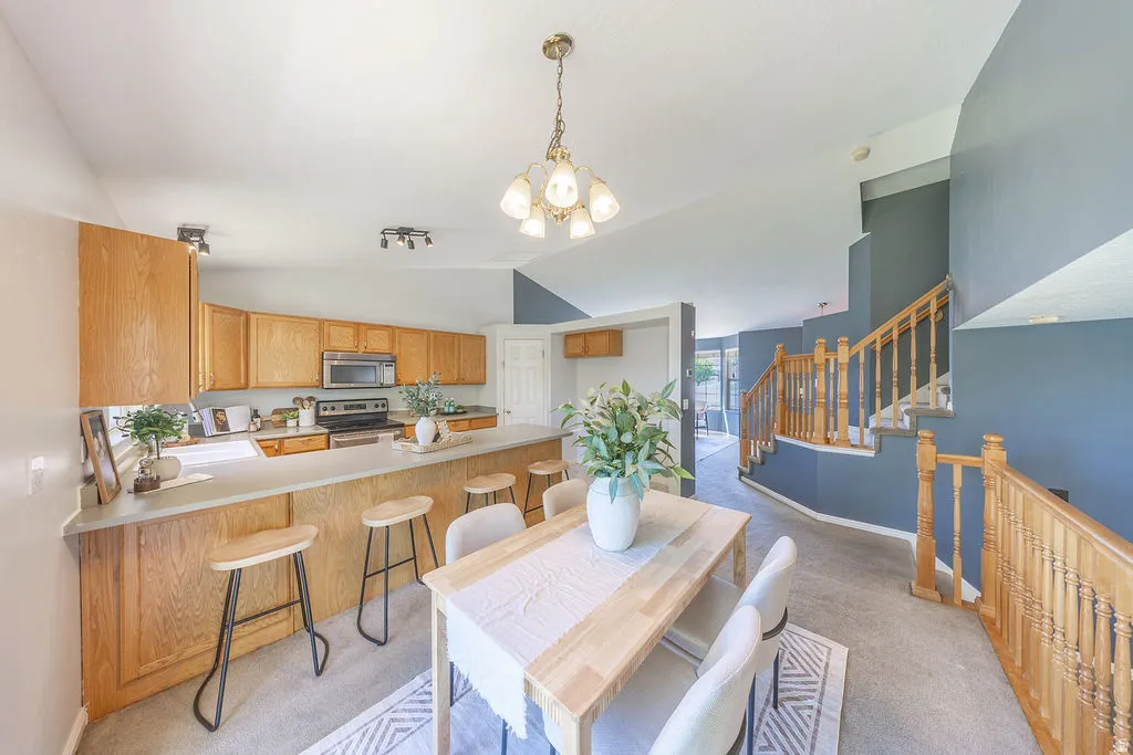 Open-concept living space.  Kitchen with wood cabinetry, stainless steel appliances, and an eat-at counter, complementing the adjacent dining area.