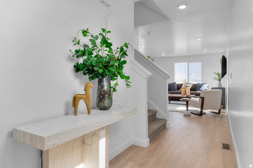 Light-toned wood-finish flooring extends through the open concept living areas, complemented by white walls and recessed lighting