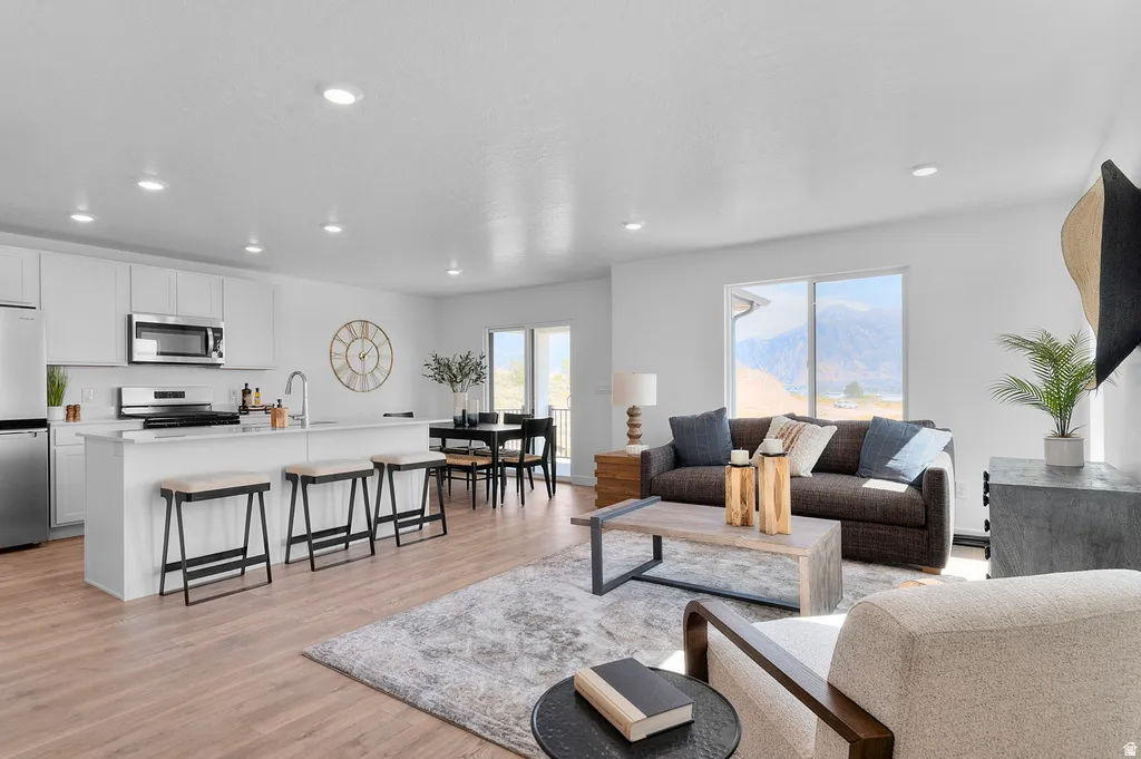 Open-concept living space featuring wood-finish flooring, recessed lighting, and white walls