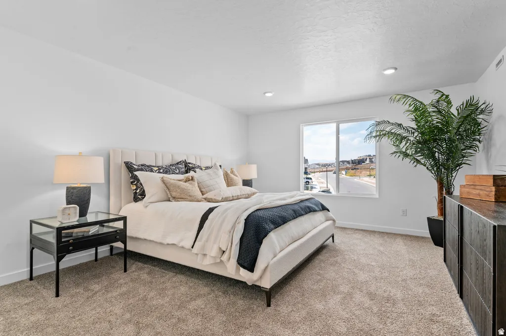 Spacious bedroom featuring plush carpet flooring, a large window, recessed lighting, and a paneled accent wall