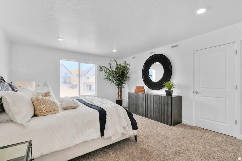 Bright interior room featuring a large window, recessed lighting, white walls, and neutral-toned carpeting