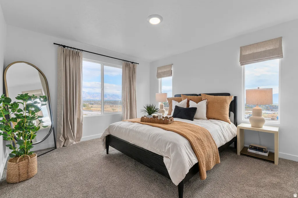 Spacious bedroom featuring multiple windows with mountain scenery, plush carpeting, and recessed lighting