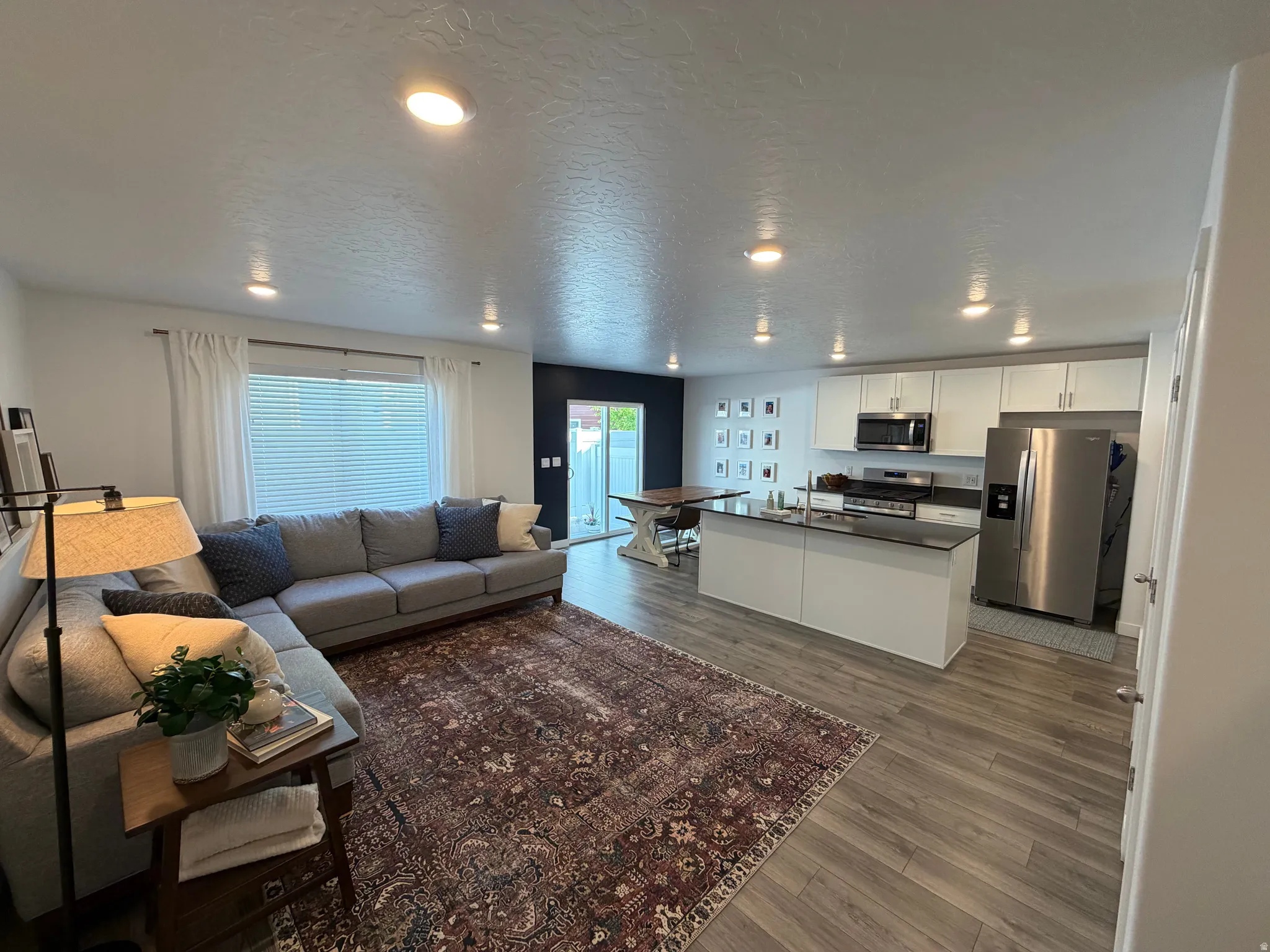 Open-concept living space featuring wood-finish flooring, recessed lighting, and a sliding glass door