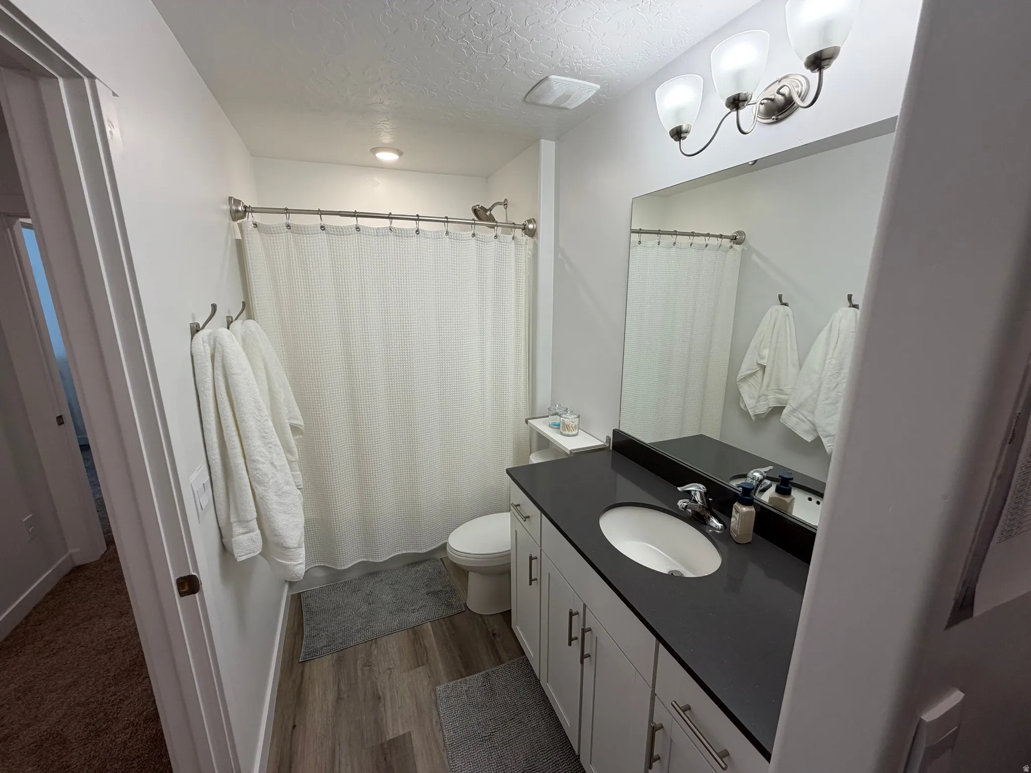Bathroom featuring a single vanity with a dark countertop, white cabinetry, and brushed nickel hardware