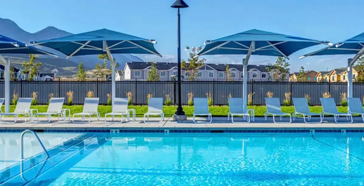 Outdoor swimming pool featuring a tiled edge and metal handrail