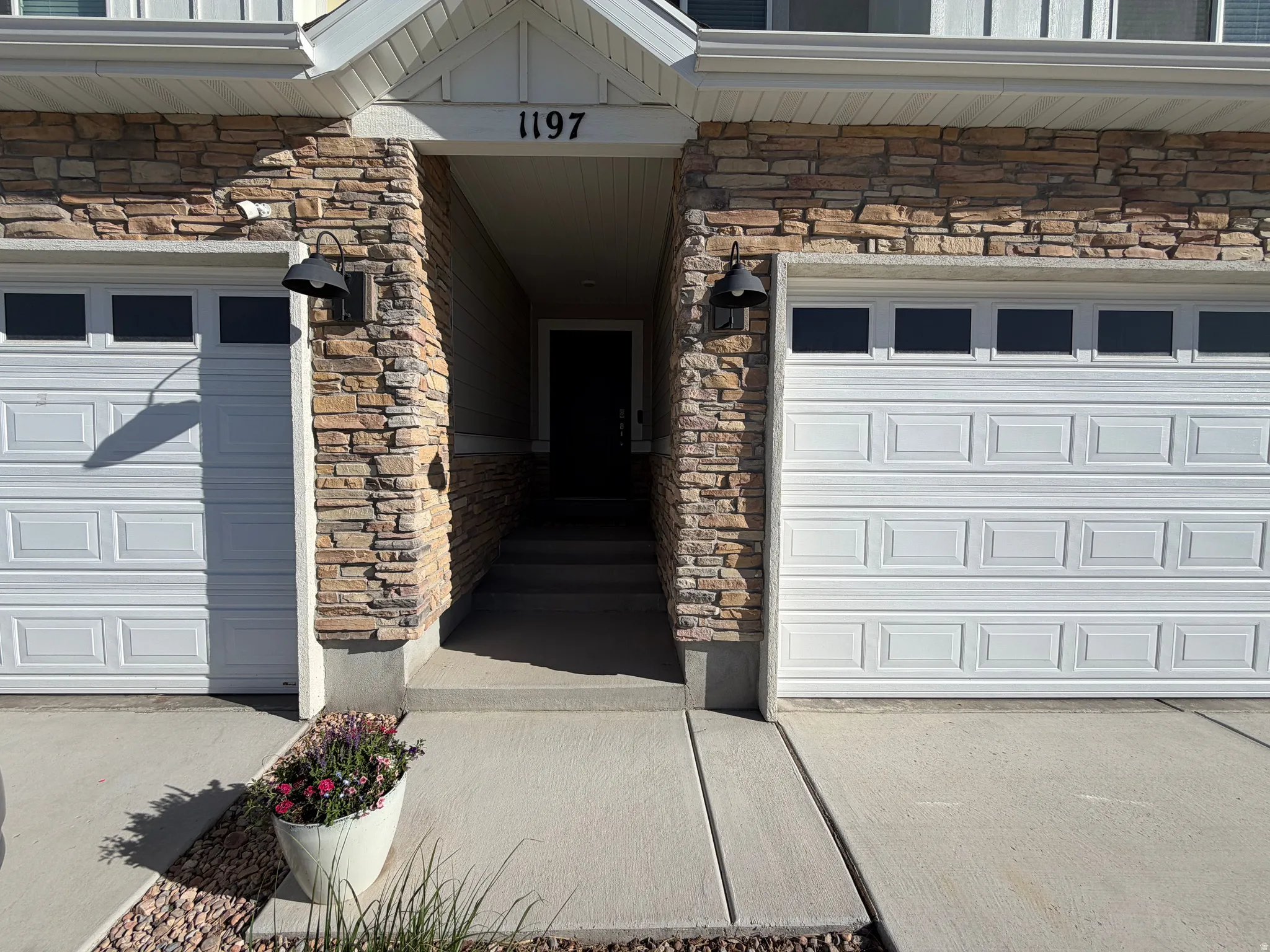 Stone veneer facade framing the recessed entry and dual white garage doors