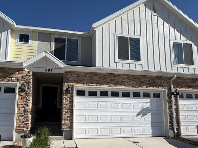 Townhome exterior featuring board and batten siding, stone veneer accents, and an attached two-car garage