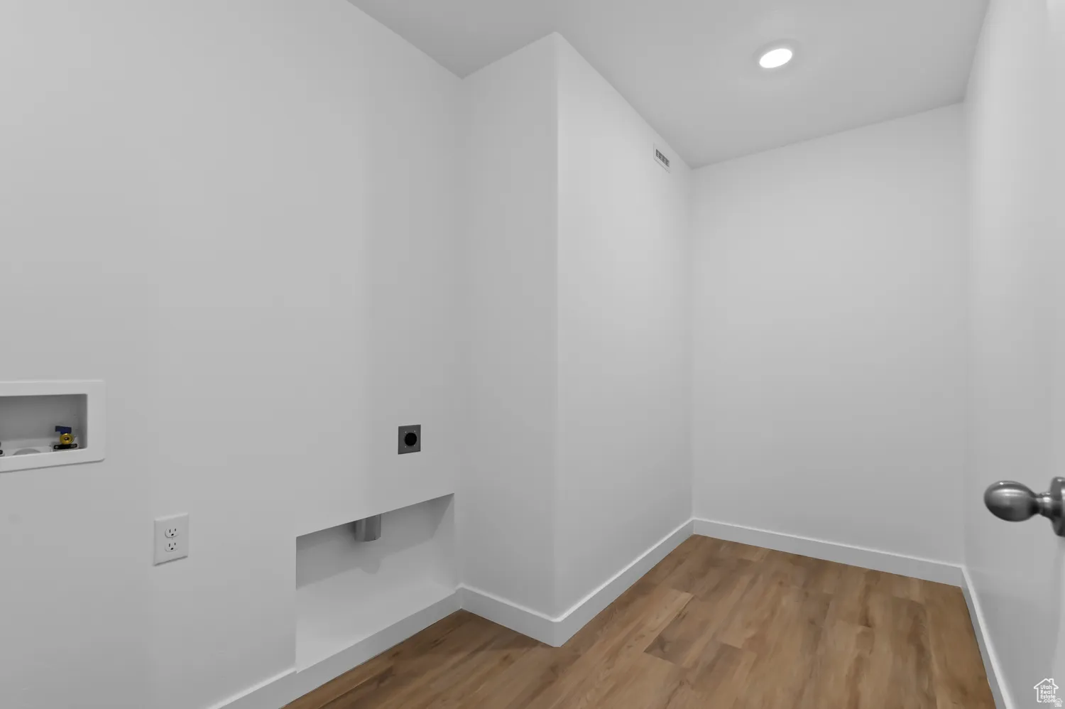 Dedicated laundry area featuring a wood-finish floor, white walls, and a ceiling-mounted recessed light