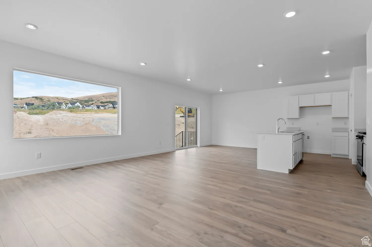 Open-concept living space featuring wood-finish flooring, recessed lighting, and a large picture window