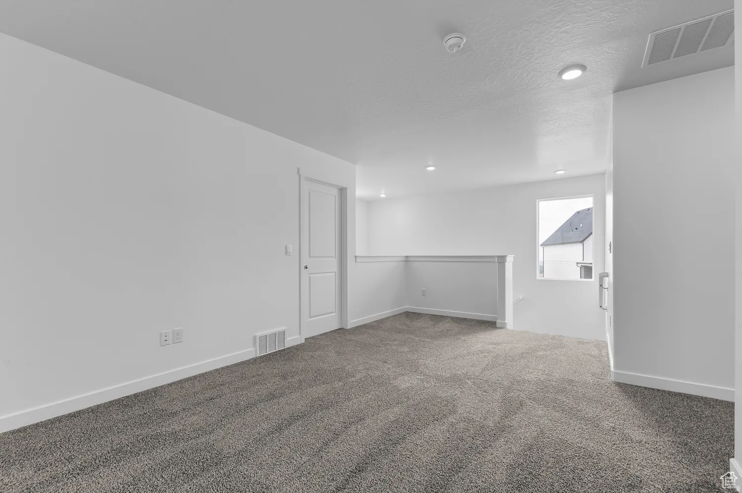 Carpeted room with recessed lighting and a window