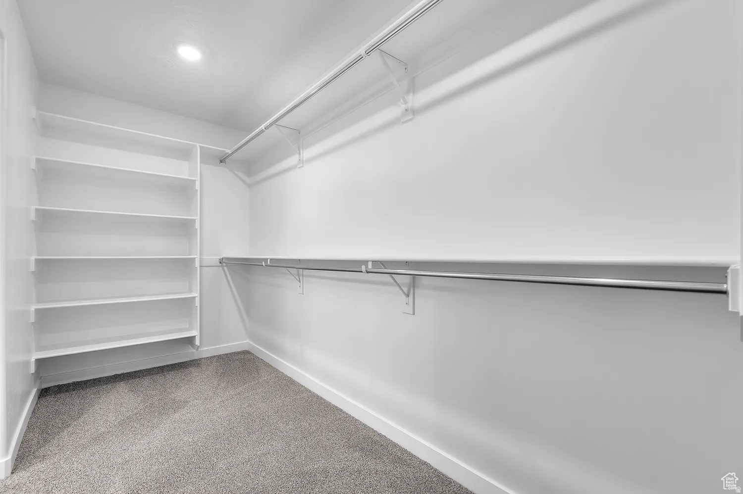Walk-in closet featuring built-in shelving, dual hanging rods, and recessed lighting
