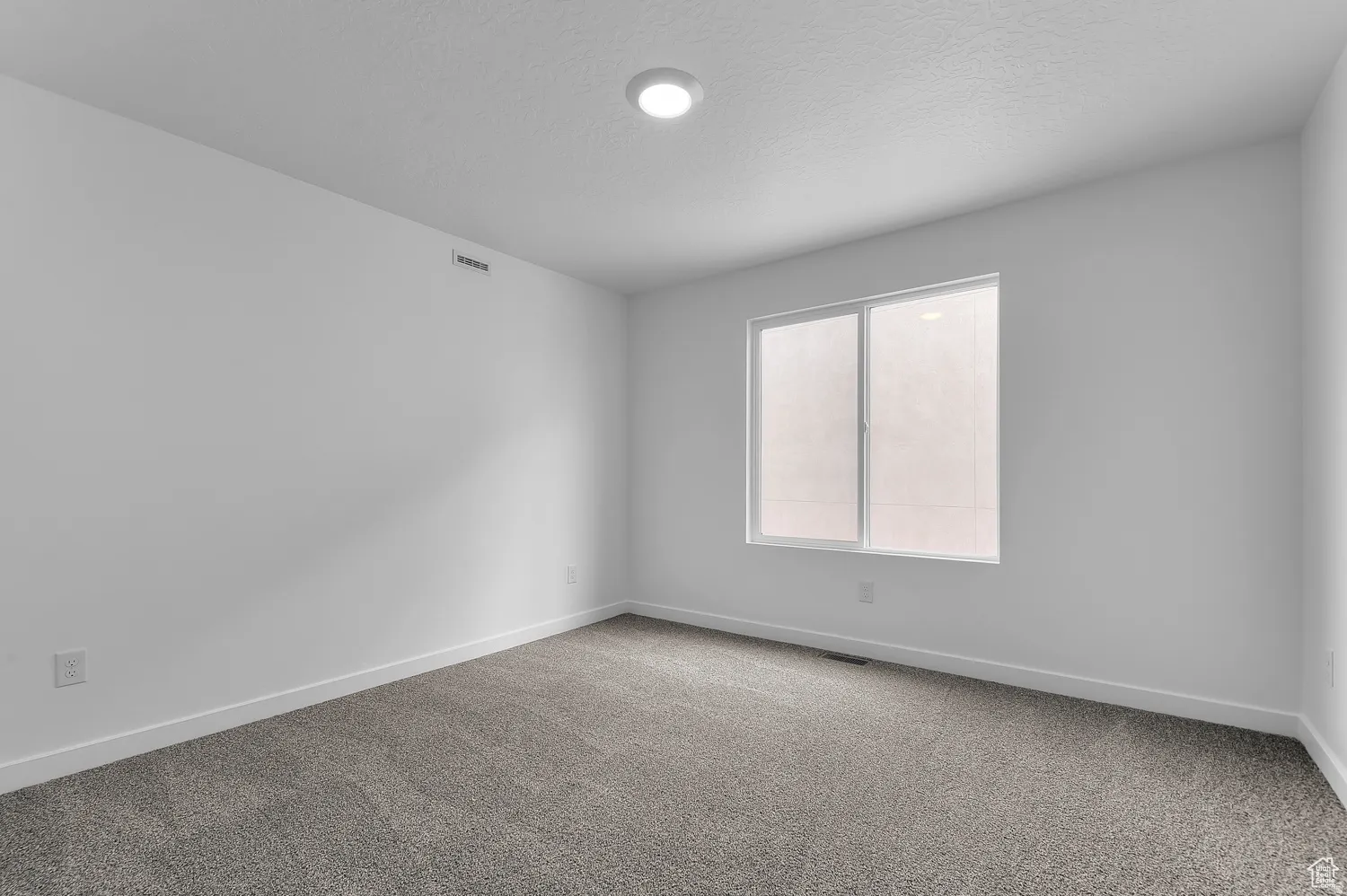 Bright room featuring a large window, recessed ceiling lighting, textured carpet, white walls, and white baseboards