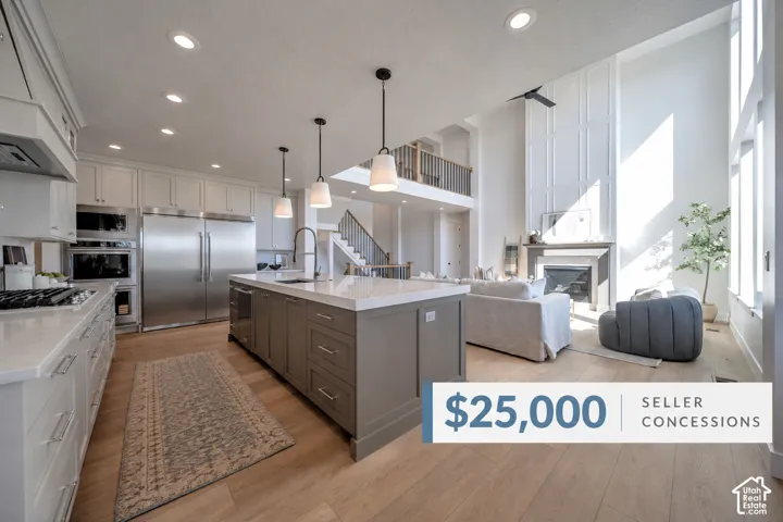 Gourmet kitchen with stainless steel appliances, large center island with pendant lighting, wood-finish flooring throughout, and a two-story living area with fireplace