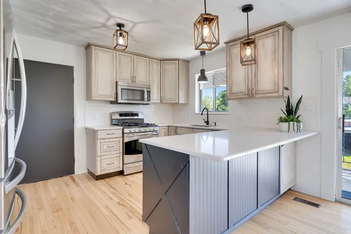Modern kitchen featuring light wood-finish flooring, white subway tile backsplash, and light-toned cabinetry