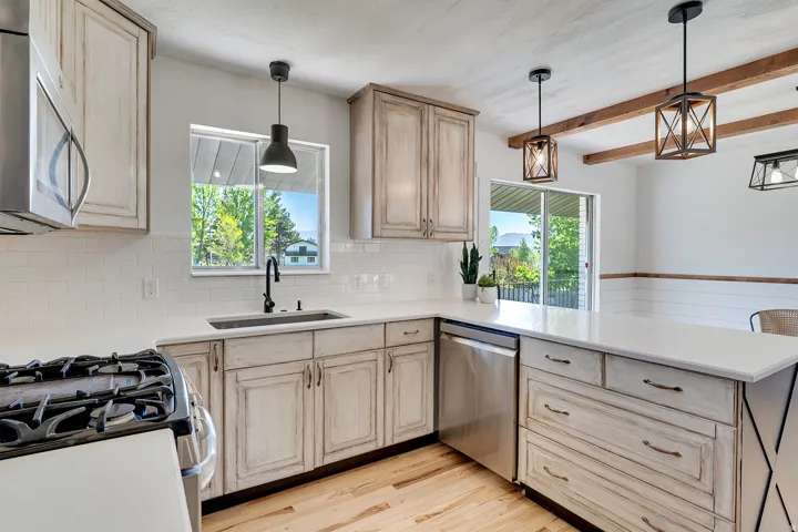 Kitchen featuring light wood-finish cabinetry, white subway tile backsplash, stainless steel appliances, and a gas range
