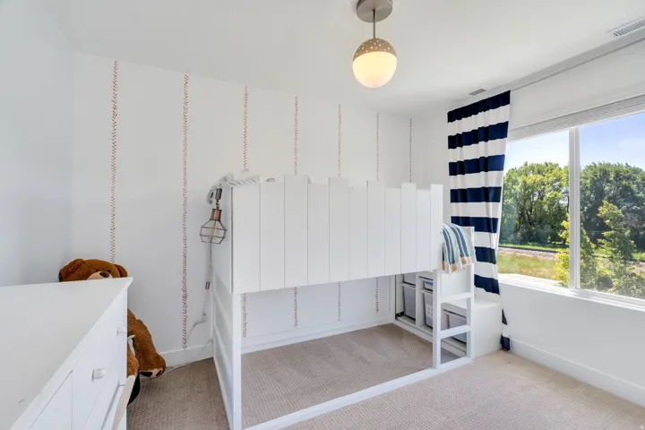 Room featuring a large window, light-colored carpeting, and a built-in bed frame with storage