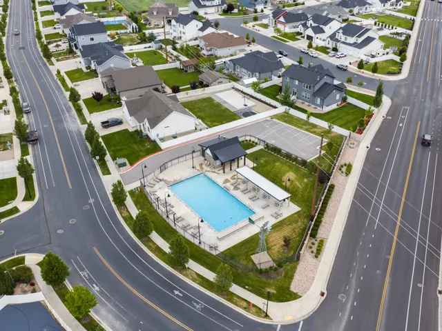 Community amenities featuring an outdoor swimming pool with an adjacent covered lounge area, a sports court, and mature landscaping