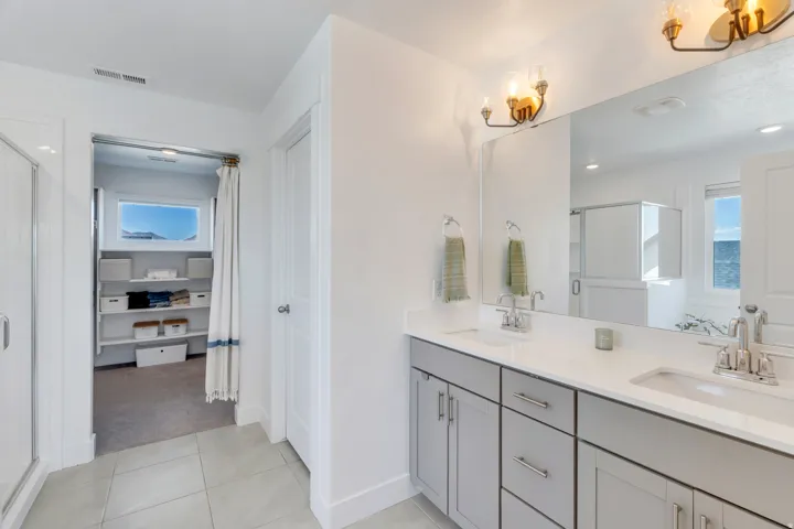 Dual vanity with light gray cabinetry, chrome hardware, undermount sinks, and white countertops