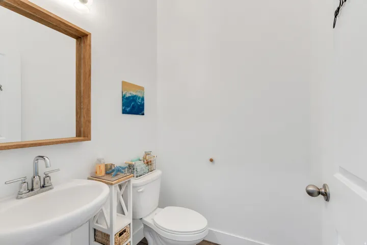 Pedestal sink with chrome faucet, framed mirror, and recessed lighting