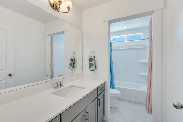 Bathroom featuring a spacious vanity with an integrated sink, polished chrome faucet, and gray cabinetry